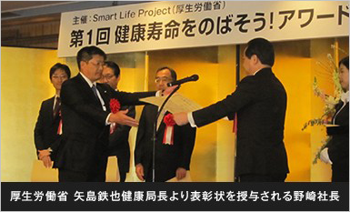 厚生労働省 矢島鉄也健康局長より表彰状を授与される野崎社長